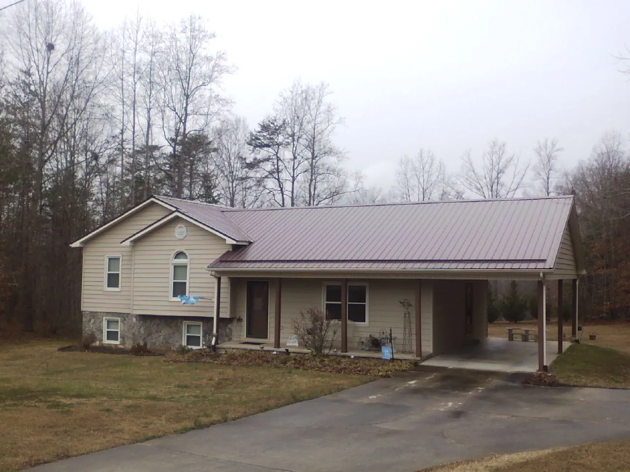Burgundy metal roof on a tan split level home with an attached carport in Valley Springs