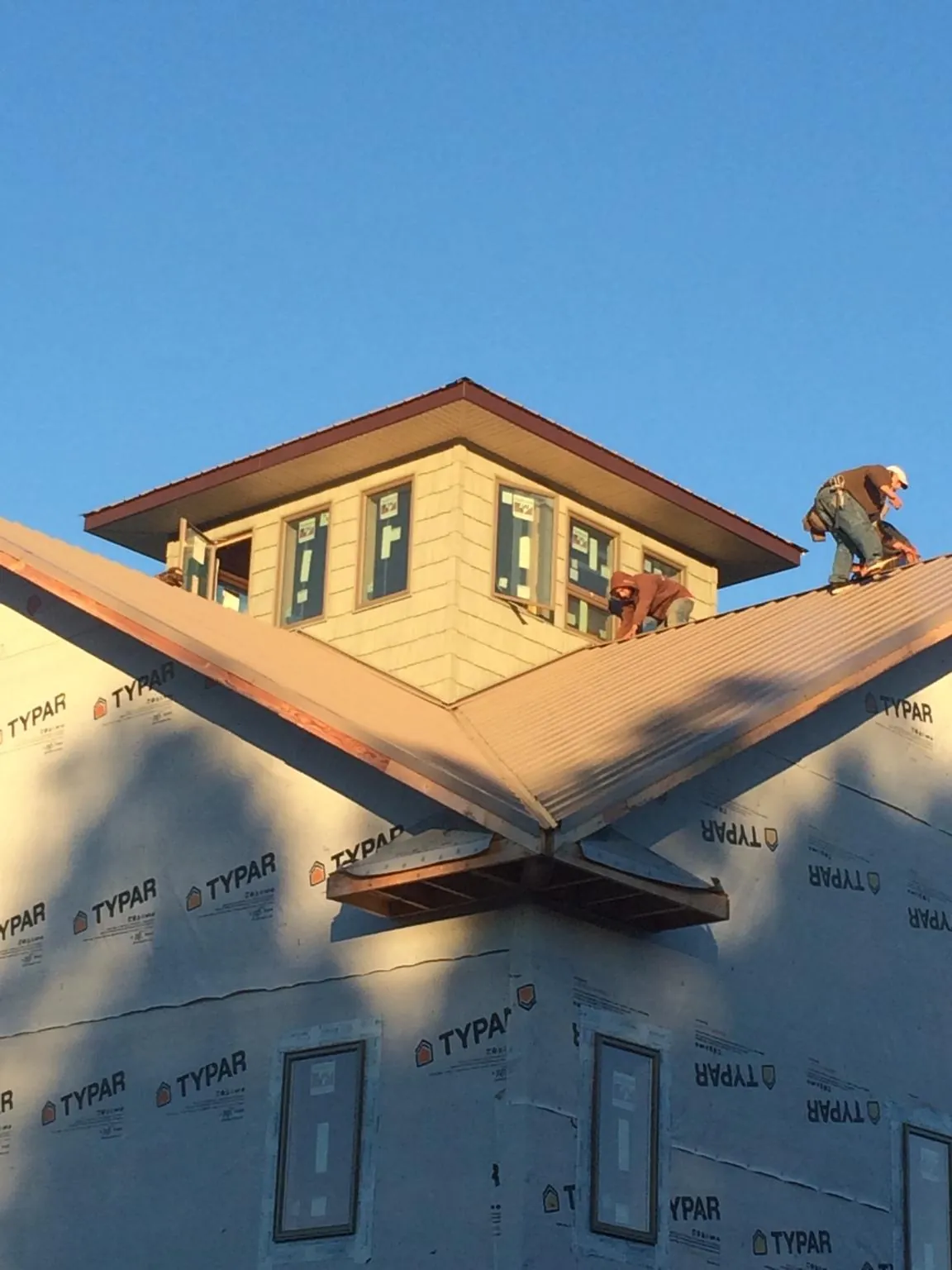 Roofers working around a rooftop cupola on a new metal roof at sunset — Roof Waterproofing in Valley Springs by Roofing Brothers